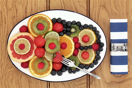 simsearch:400-08618279,k - Fruit selection for antioxidant  health food diet on an oval plate with old silver fork and napkin with ring over oak background. Photographie de stock - Aubaine LD & Abonnement, Code: 400-07993806