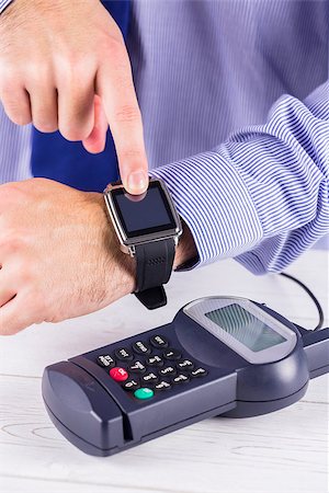 simsearch:400-08017447,k - Man using smart watch to express pay  on a wooden table Fotografie stock - Microstock e Abbonamento, Codice: 400-08017419