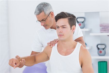 simsearch:400-04337005,k - Doctor stretching a young man arm in medical office Foto de stock - Super Valor sin royalties y Suscripción, Código: 400-08018565