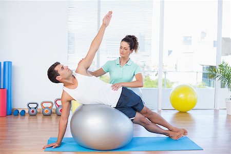 simsearch:400-07925663,k - Trainer helping man with exercise ball in fitness studio Stockbilder - Microstock & Abonnement, Bildnummer: 400-08018957