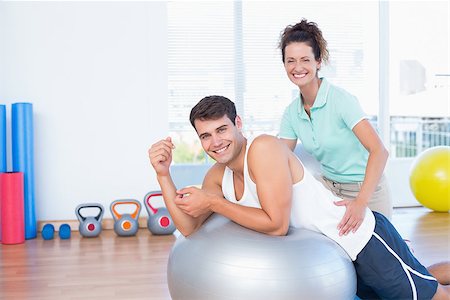 simsearch:400-07925663,k - Trainer helping man with exercise ball in fitness studio Stockbilder - Microstock & Abonnement, Bildnummer: 400-08018951