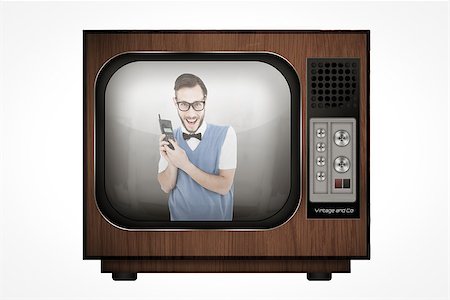 Geeky hipster holding a retro cellphone against retro tv Stock Photo - Budget Royalty-Free & Subscription, Code: 400-08019250