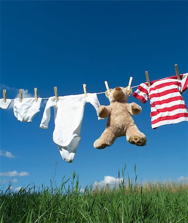 simsearch:695-05769527,k - Baby Clothing and a teddybear on a clothesline towards blue sky Photographie de stock - Aubaine LD & Abonnement, Code: 400-08011683