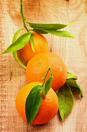 simsearch:400-08012355,k - Three Fresh Ripe Tangerines with Stems and Leafs In a Row closeup on Rustic Wooden background Photographie de stock - Aubaine LD & Abonnement, Code: 400-08011836