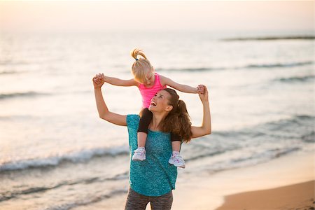 simsearch:400-06867373,k - Happy baby girl sitting on shoulders of mother on beach in the evening Stockbilder - Microstock & Abonnement, Bildnummer: 400-08021557