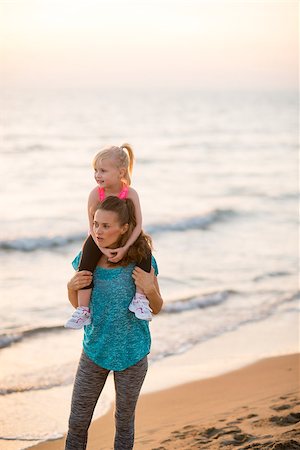 simsearch:400-06867373,k - Happy baby girl sitting on shoulders of mother on beach in the evening and looking into distance Stockbilder - Microstock & Abonnement, Bildnummer: 400-08021559