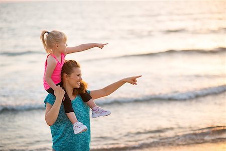 simsearch:400-06867373,k - Happy baby girl sitting on shoulders of mother on beach in the evening and pointing Stockbilder - Microstock & Abonnement, Bildnummer: 400-08021560