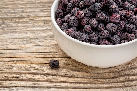 simsearch:400-08334670,k - Dried chokeberry (aronia berry) in a small, ceramic bowl against grained wood Stock Photo - Budget Royalty-Free & Subscription, Code: 400-08021885