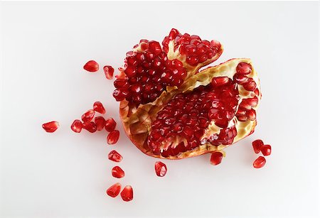 simsearch:693-08127360,k - Part of delicious juicy ripe pomegranate and pomegranate seeds scattered around. Studio shot. Top view. Photographie de stock - Aubaine LD & Abonnement, Code: 400-08021936