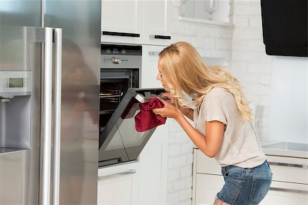 simsearch:400-08021946,k - very pretty young blond woman , in act of looking some food with oven in her luxury white modern kitchen Stock Photo - Budget Royalty-Free & Subscription, Code: 400-08021945