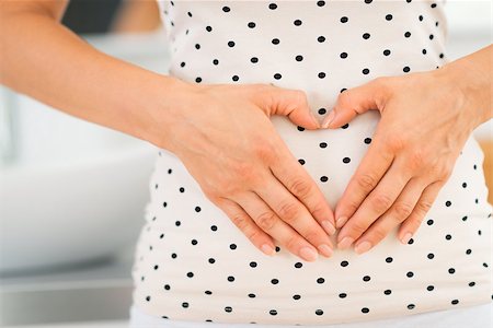 simsearch:400-06690931,k - Closeup on young woman holding hands in heart shape on her belly Fotografie stock - Microstock e Abbonamento, Codice: 400-08022544