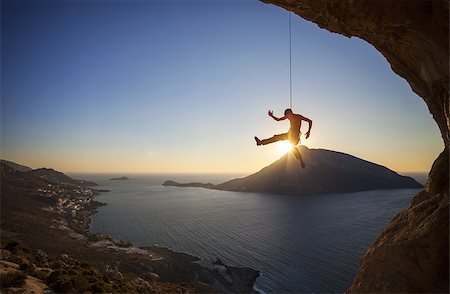spartanisch - Rock climber hanging on rope while lead climbing at sunset, with Telendos island in background Stockbilder - Microstock & Abonnement, Bildnummer: 400-08035134