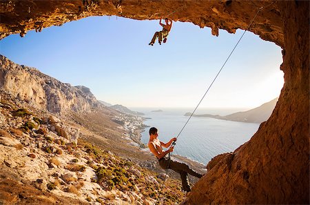 simsearch:400-08072896,k - Male rock climber climbing on a roof in a cave, his partner belaying Foto de stock - Royalty-Free Super Valor e Assinatura, Número: 400-08035143