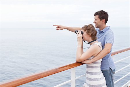 family on yacht - couple enjoying cruise, woman looking through binoculars and man showing something ahead Stock Photo - Budget Royalty-Free & Subscription, Code: 400-08035925