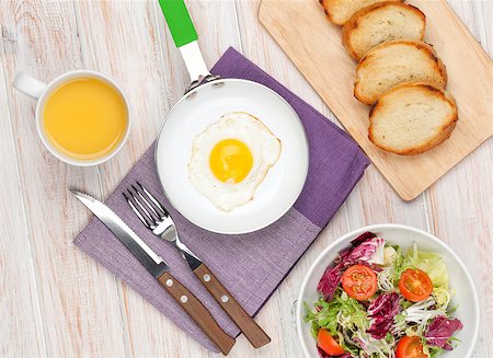Healthy breakfast with fried egg, toasts and salad on white wooden table Stock Photo - Budget Royalty-Free & Subscription, Code: 400-08037262