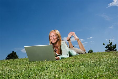Woman with computer in the grass towards blue sky Stock Photo - Budget Royalty-Free & Subscription, Code: 400-08032422