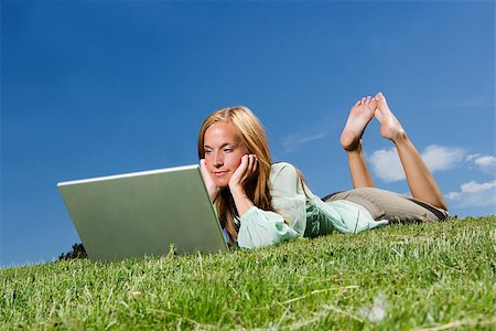 Woman with computer in the grass towards blue sky Photographie de stock - Aubaine LD & Abonnement, Code: 400-08032423