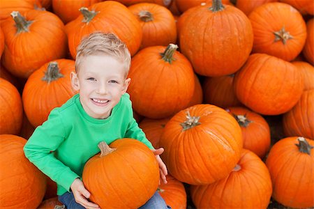 simsearch:400-07169847,k - little excited kid looking up enjoying time at pumpkin patch sitting in the huge pile of pumpkins Photographie de stock - Aubaine LD & Abonnement, Code: 400-08046457