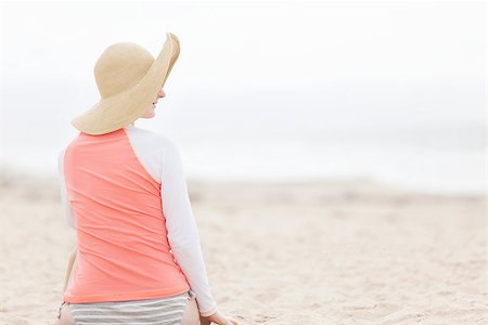 young woman enjoying beach vacation and protecting skin against harmful UV rays with rashguard Foto de stock - Super Valor sin royalties y Suscripción, Código: 400-08046458
