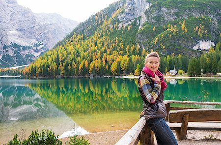 simsearch:400-08054038,k - A smiling brunette hiker at Lake Bries wearing outdoor gear is resting against a wooden railing, holding her pink scarf. The still water, autumn colours and shades of green and gray create an autumn background. The water provides a mirror image of the scenery. Photographie de stock - Aubaine LD & Abonnement, Code: 400-08054025