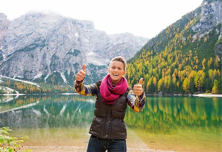 simsearch:400-08054037,k - A smiling and laughing brunette holding two thumbs up in approval while standing on the shores of Lake Bries. In the background, the still water reflects the autumn colours in the trees, and the Dolomite mountains. The great outdoors at their finest. Stock Photo - Budget Royalty-Free & Subscription, Code: 400-08054033