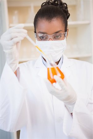 simsearch:400-08055396,k - Concentrated scientist examining orange fluid with pipette in laboratory Stock Photo - Budget Royalty-Free & Subscription, Code: 400-08055385