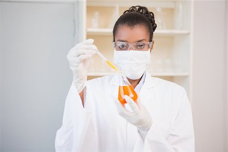 simsearch:400-08055390,k - Concentrated scientist examining orange fluid with pipette in laboratory Stock Photo - Budget Royalty-Free & Subscription, Code: 400-08055386