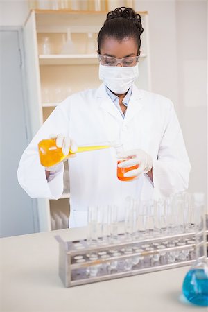 simsearch:400-08055357,k - Concentrated scientist pouring orange fluid in laboratory Stock Photo - Budget Royalty-Free & Subscription, Code: 400-08055387