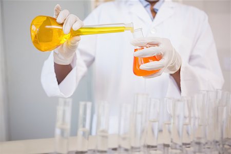 simsearch:400-08055396,k - Concentrated scientist pouring orange fluid in laboratory Stock Photo - Budget Royalty-Free & Subscription, Code: 400-08055388