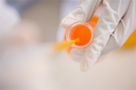 simsearch:400-08055390,k - Scientist examining orange fluid in laboratory Stock Photo - Budget Royalty-Free & Subscription, Code: 400-08055391
