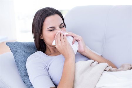 simsearch:400-06801081,k - Sick brunette lying on the couch and blowing her nose in the living room Photographie de stock - Aubaine LD & Abonnement, Code: 400-08055886