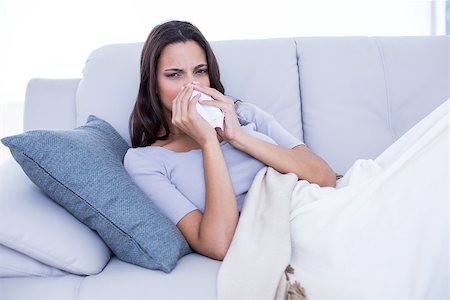 simsearch:400-06801081,k - Sick brunette lying on the couch and blowing her nose in the living room Photographie de stock - Aubaine LD & Abonnement, Code: 400-08055887