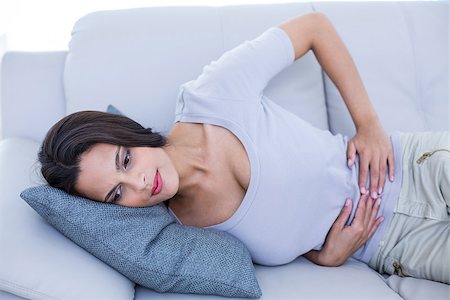 flat tummy women - Sick brunette having stomachache in the living room Stock Photo - Budget Royalty-Free & Subscription, Code: 400-08055889