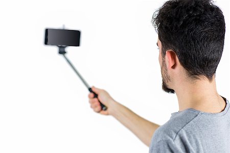 selfie stick - Casual man using a selfie stick shot in studio Stock Photo - Budget Royalty-Free & Subscription, Code: 400-08056420
