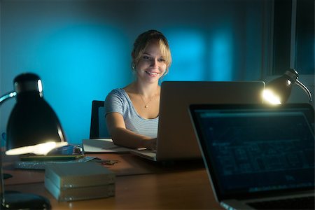 Beautiful woman working as interior designer, staying late at night in office with drawings and laptop computer to complete a project. The girl gets an idea and smiles. Stock Photo - Budget Royalty-Free & Subscription, Code: 400-08051962