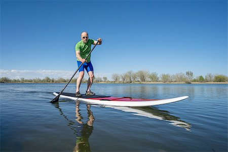 simsearch:400-07795226,k - Senior male exercising on stand up paddling (SUP) board. Early spring on a calm lake in Fort Collins, Colorado.. Foto de stock - Royalty-Free Super Valor e Assinatura, Número: 400-08052554