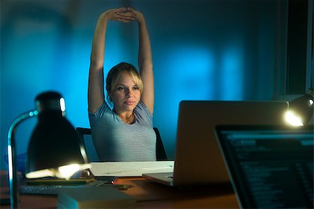 Beautiful woman working as interior designer, staying late at night in office with drawings and laptop computer to complete a project. The girl yawns and stretch her arms Stock Photo - Budget Royalty-Free & Subscription, Code: 400-08052551