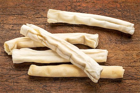 small rawhide bones - dog treats on grunge wood background Stock Photo - Budget Royalty-Free & Subscription, Code: 400-08053720