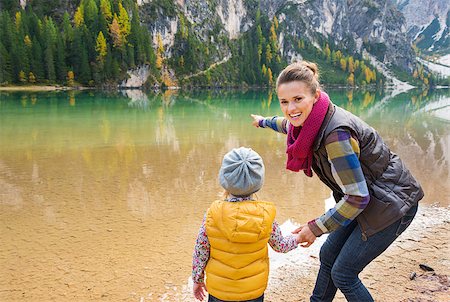 simsearch:400-08054003,k - Did you see that? A mother in hiking gear smiling and pointing out to the lake. Seen from behind, her daughter is looking out at the lake and holding her mother's hand. Fall colours. Photographie de stock - Aubaine LD & Abonnement, Code: 400-08053994