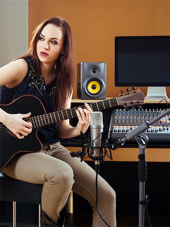 Photo of a beautiful brunette in a recording studio recording her guitar tracks. Stock Photo - Budget Royalty-Free & Subscription, Code: 400-08074430