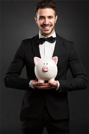 simsearch:400-05715051,k - Man in tuxedo holding a pig money box Fotografie stock - Microstock e Abbonamento, Codice: 400-08074633