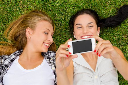 simsearch:400-07303759,k - Female best friends lying on the grass and taking selfies Stockbilder - Microstock & Abonnement, Bildnummer: 400-08074646