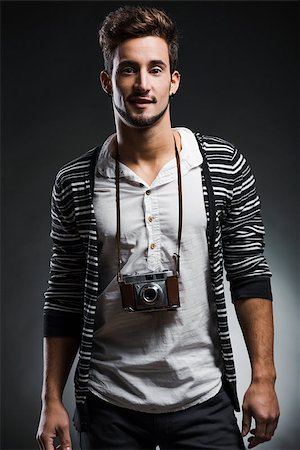 Studio portrait of a fashion young man posing with a old photographic camera, over a dark background Stock Photo - Budget Royalty-Free & Subscription, Code: 400-08075055