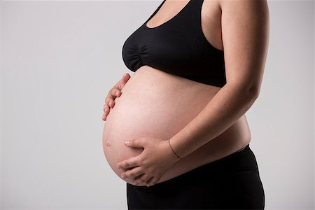 simsearch:400-04859723,k - Pregnant woman showing her belly, over a gray background Fotografie stock - Microstock e Abbonamento, Codice: 400-08075057