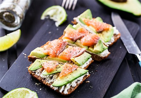 sandwich with avocado - Sandwich with avocado and smoked salmon on a black wooden board Stock Photo - Budget Royalty-Free & Subscription, Code: 400-08075114