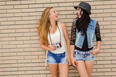 simsearch:400-04585942,k - Two beautiful and young girlfriends having fun, in front of a brick wall Photographie de stock - Aubaine LD & Abonnement, Code: 400-08075275