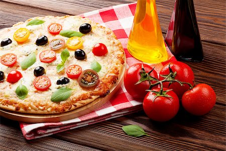 simsearch:400-08960199,k - Italian pizza with cheese, tomatoes, olives and basil on wooden table Stock Photo - Budget Royalty-Free & Subscription, Code: 400-08075670