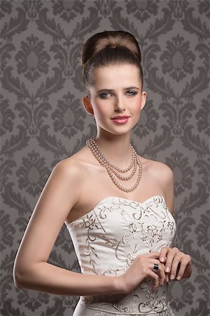 simsearch:400-07822212,k - very pretty woman with elegant style. Wearing white decorated dress, pearls necklace and classic hairdo. Looking in camera and smiling with calm expression Fotografie stock - Microstock e Abbonamento, Codice: 400-08076192