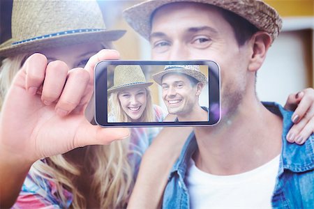 simsearch:400-07664794,k - Hand holding smartphone showing against hip young couple smiling at camera Stock Photo - Budget Royalty-Free & Subscription, Code: 400-08076796