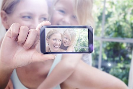 simsearch:400-07664794,k - Hand holding smartphone showing against cute little girl and mother on bed Stock Photo - Budget Royalty-Free & Subscription, Code: 400-08076825